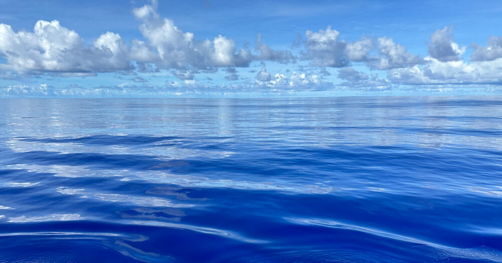 Bright blue ocean horizon with clouds.